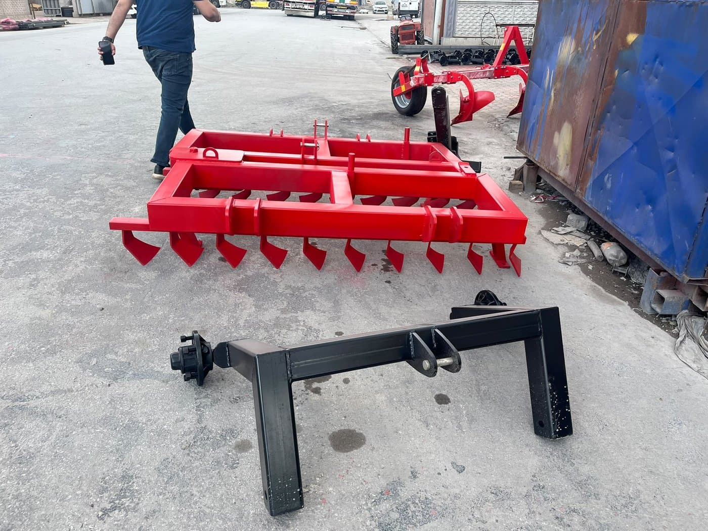 Tined cultivator frame beside a trailer axle assembly