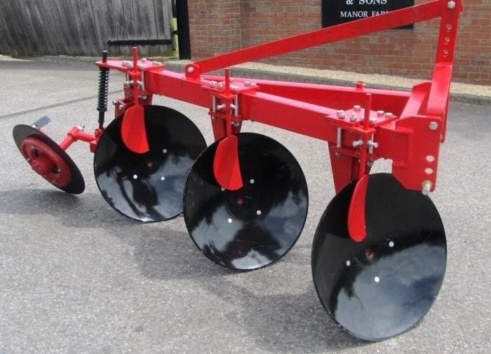 Three disc plough against a brick wall backdrop