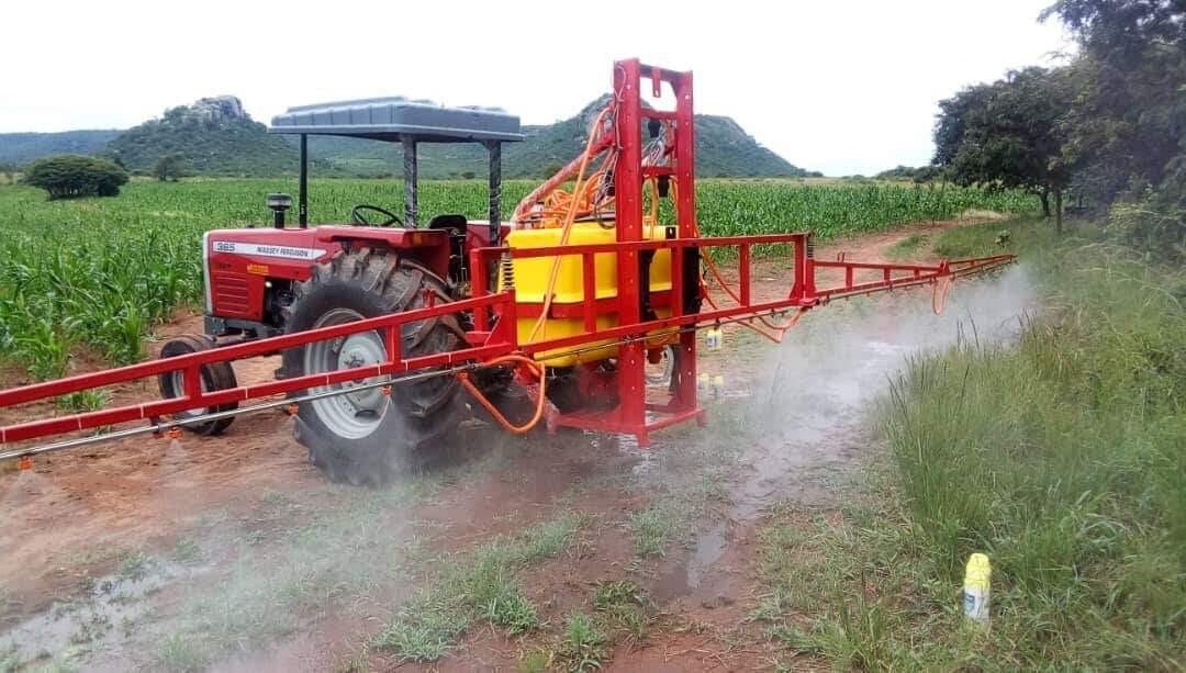 Massey Ferguson tractor fitted with a boom sprayer, spraying a maize field
