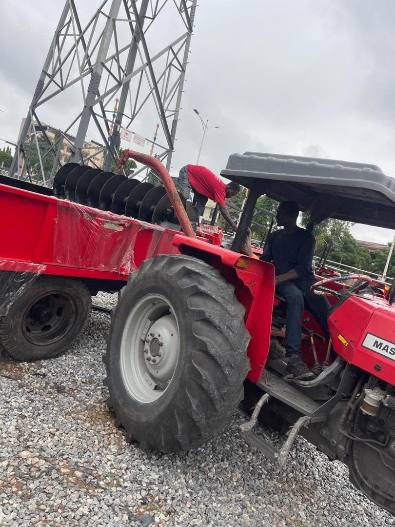 Tractor and disc harrow staged for delivery near a power pylon