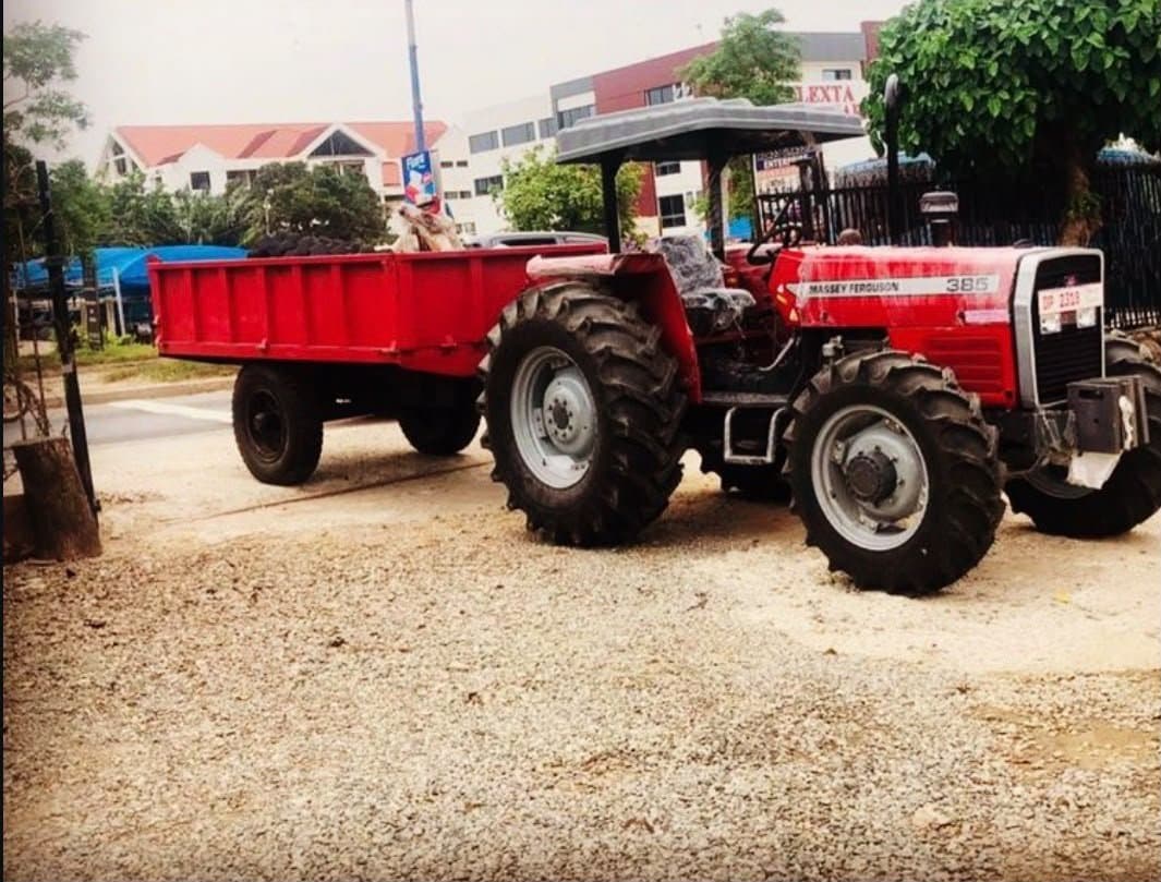 Massey Ferguson 385 tractor hitched to a trailer on a delivery route