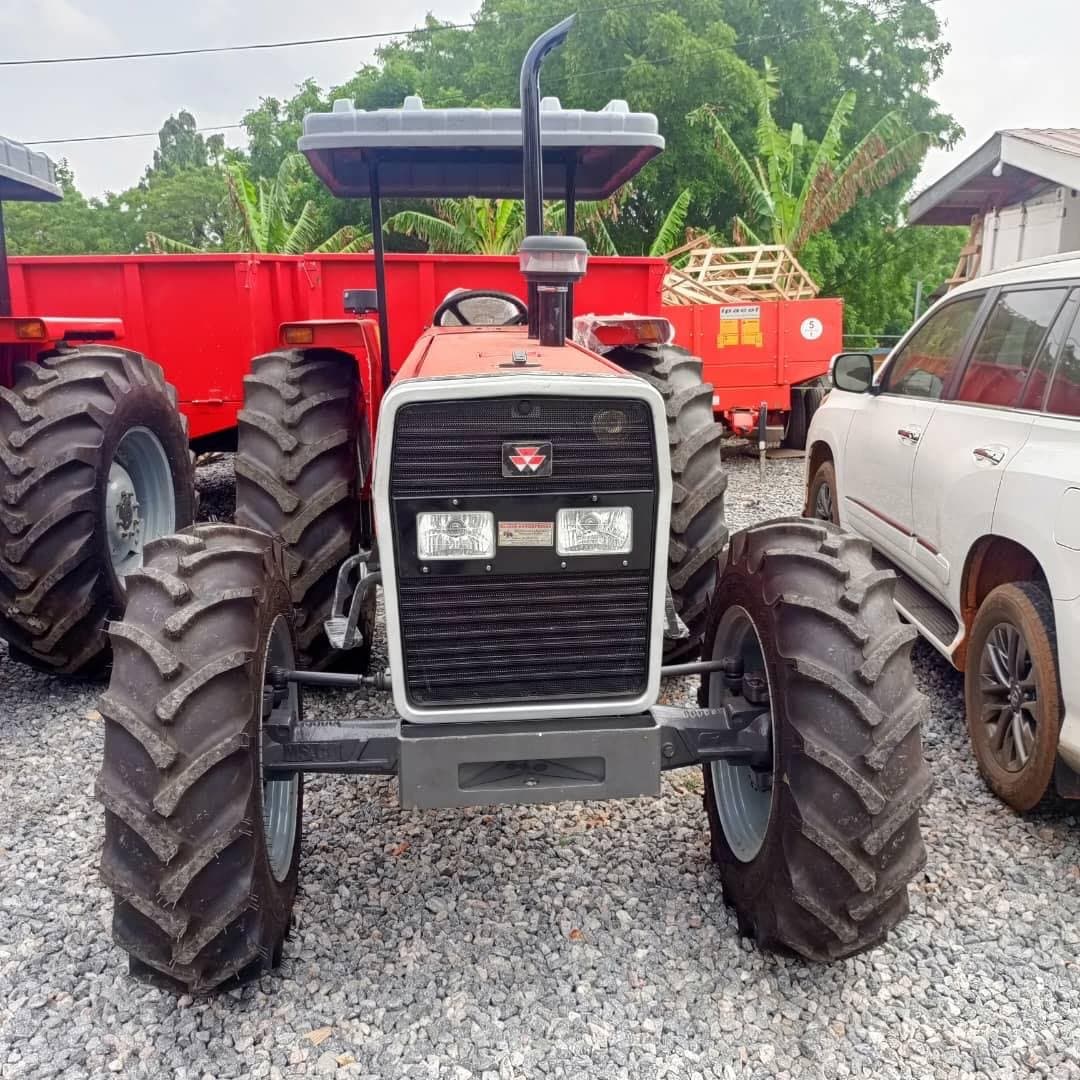 Front view of a Massey Ferguson 385 tractor beside a loaded trailer
