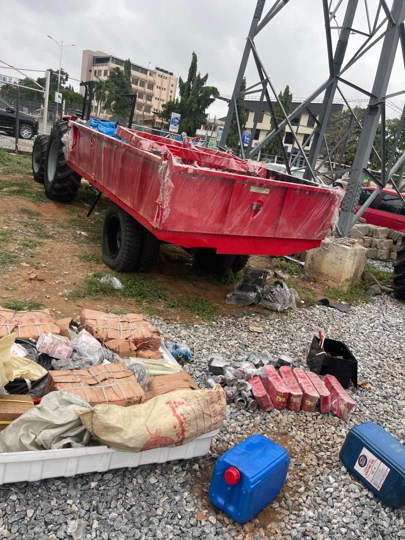 Trailer and machinery parts staged for delivery near a power pylon